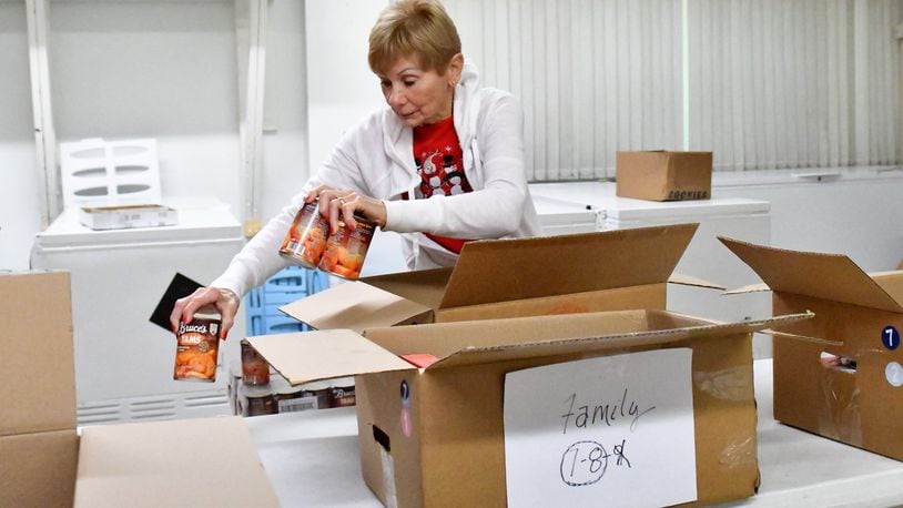 A volunteer works to pack boxes at Needy Basket. CONTRIBUTED