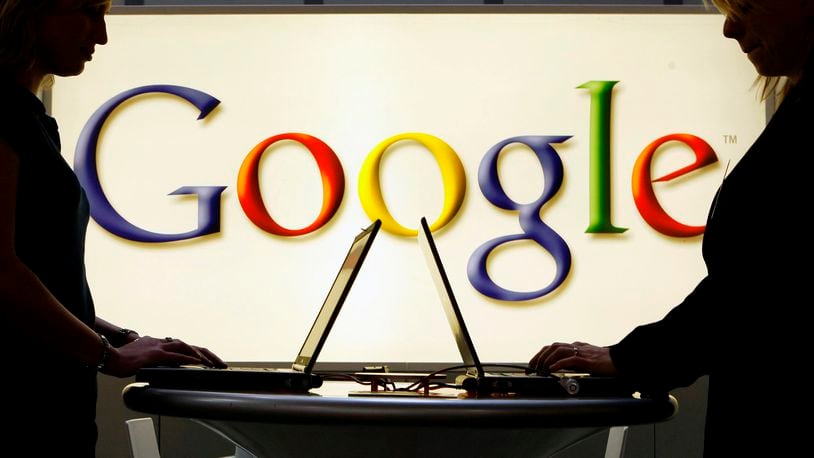 FILE - In this April 17, 2007 file photo, exhibitors work on laptop computers in front of an illuminated sign of the Google logo at the industrial fair Hannover Messe in Hanover, Germany. (AP Photo/Jens Meyer, File)