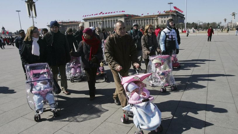 FILE- Spanish couples take their newly adopted Chinese children for a walk in Beijing's Tiananmen Square, March 7, 2007. (AP Photo/Greg Baker, File)