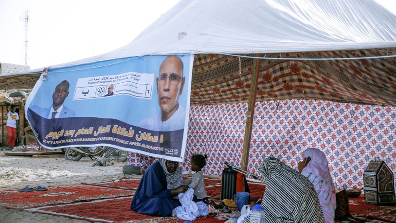 Women sit behind an electoral banner for Mauritanian president Mohamed Ould Ghazouani, during a campaign rally ahead of the presidential elections in Nouakchott, Mauritania, Wednesday, June 26, 2024. The banner reads: "There is no place for people embezzling public funds anymore." (AP Photo/Mamsy Elkeihel)