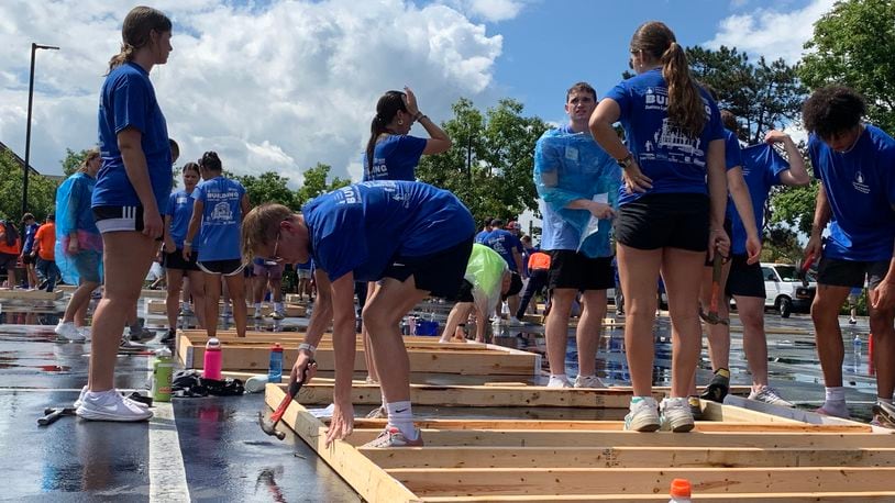 More than 400 University of Dayton students braved pouring rain Sunday to build wood frame walls for Dayton Habitat for Humanity. LONDON BISHOP/STAFF