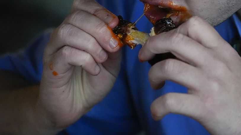 A man eats a chicken wing, Wednesday, June 12, 2024, at a barbecue restaurant in Cincinnati. Psychologists have known for years now that men tend to eat more meat than women, but a study of people around the world now reveals that that's true across cultures. (AP Photo/Joshua A. Bickel)