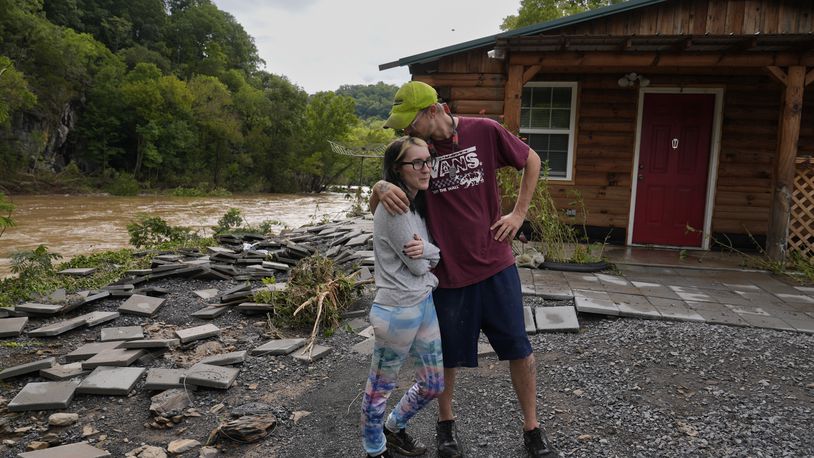 Jonah Wark, right, kisses his wife Sara Martin outside their flood damaged home on the Pigeon River, Saturday, Sept. 28, 2024, in Newport, Tenn. (AP Photo/George Walker IV)