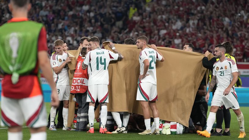 Players hold a blanket as medical personnel treat Hungary's Barnabas Varga during a Group A match between Scotland and Hungary at the Euro 2024 soccer tournament in Stuttgart, Germany, Sunday, June 23, 2024. (AP Photo/Antonio Calanni)