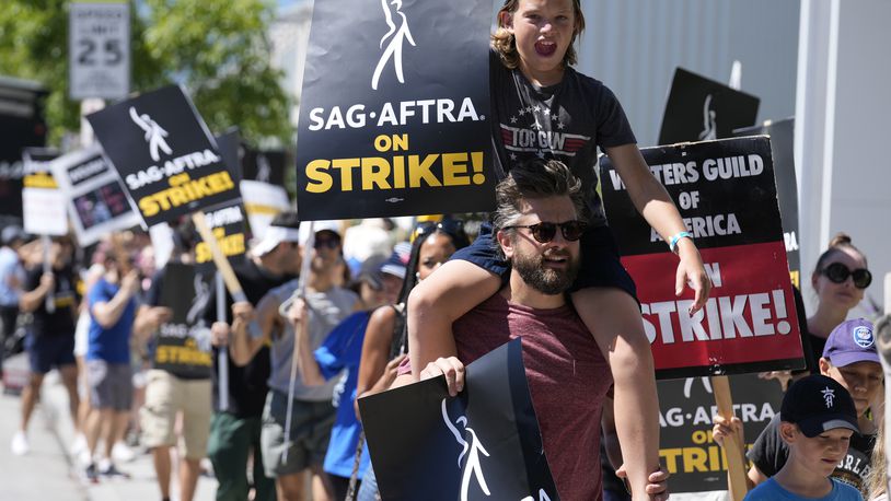 FILE - Director of Photography Jac Cheairs and his son, actor Wyatt Cheairs, 11, take part in a rally by striking writers and actors outside Netflix studio in Los Angeles on Friday, July 14, 2023. (AP Photo/Chris Pizzello, File)