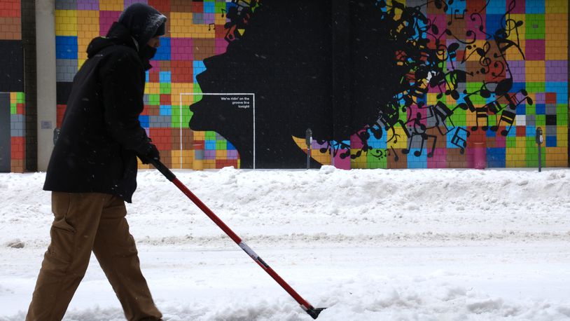 Kevin Daniels shovels snow and ice off the sidewalk along Jefferson Street in Dayton Friday.