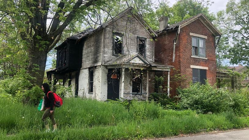 Dayton plans to demolish about 850 housing units using more than $15 million in federal rescue funds. A woman walks by two abandoned and vacant homes in East Dayton. CORNELIUS FROLIK / STAFF