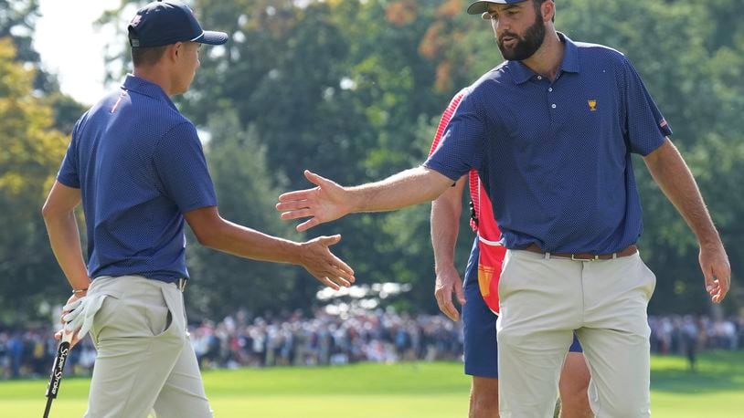 United States team member Scottie Scheffler, right, shakes hands with partner Collin Morikawa after making a putt on the 15th hole during the third round at the Presidents Cup golf tournament at Royal Montreal Golf Club in Montreal Saturday, Sept. 28, 2024. (Nathan Denette/The Canadian Press via AP)