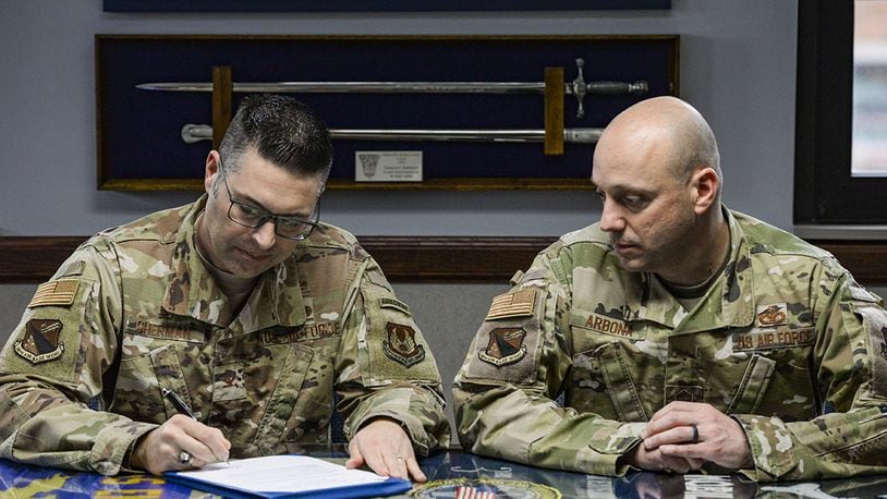 Col. Thomas Sherman, 88th Air Base Wing commander, signs the Asian American Pacific Islander Heritage Month Proclamation as Chief Master Sgt. Stephen Arbona, 88th ABW command chief, watches inside his office at Wright-Patterson Air Force Base, May 8. (U.S. Air Force photo/Wesley Farnsworth)