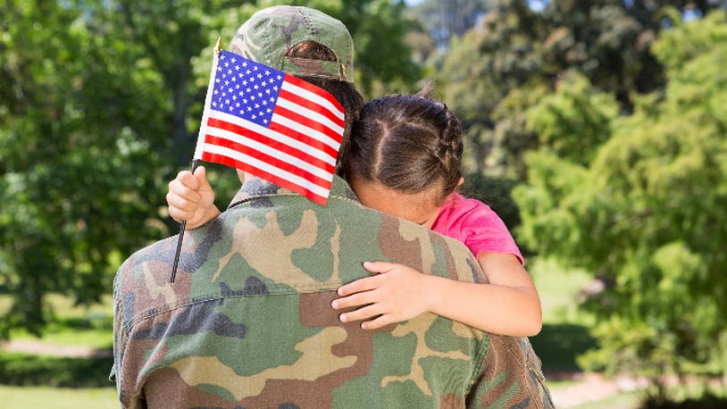 American soldier reunited with daughter on a sunny day (stock photo).