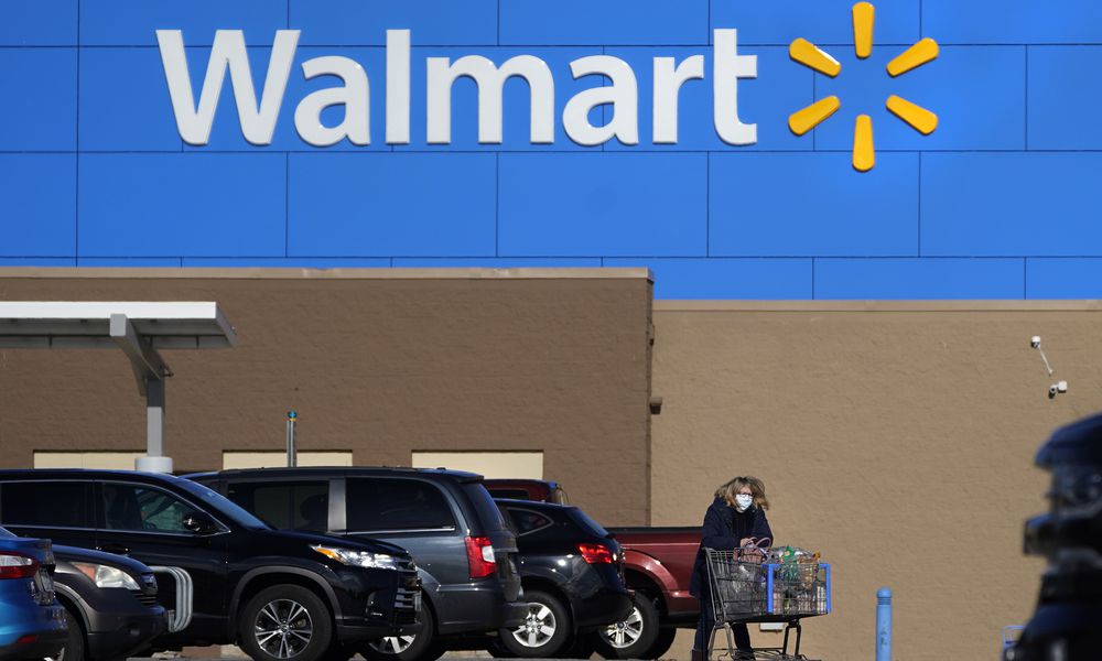 FILE - A woman wheels a cart with her purchases out of a Walmart store, Nov. 18, 2020, in Derry, N.H. (AP Photo/Charles Krupa, File)