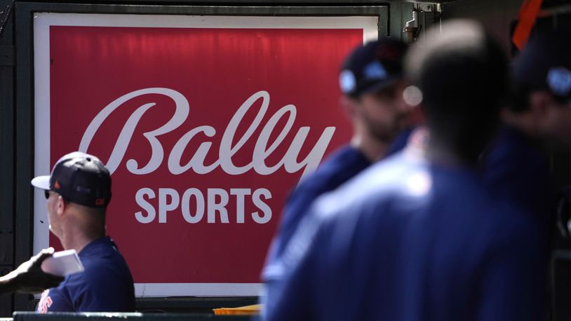 FILE - A Bally Sports sign hangs in a dugout before a spring training baseball game between the St. Louis Cardinals and the Houston Astros, March 2, 2023, in Jupiter, Fla. (AP Photo/Jeff Roberson, File)