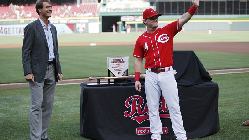 Scooter Gennett of the Reds waves to fans while standing with general manager Dick Williams during a ceremony to commemorate his four home run game from June 6 prior to a game against the Los Angeles Dodgers at Great American Ball Park.