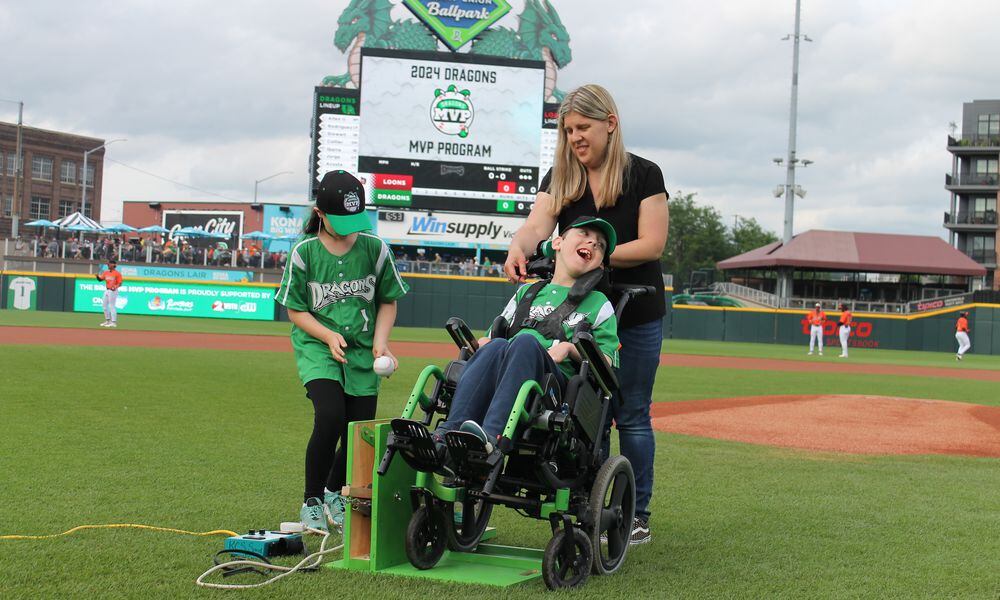 At the Dayton Dragons game Friday, May 17, 2024, Lola Zimmer (left), a student at Prass Elementary in Kettering, helped her friend Neil throw out the first pitch, using a device Lola and others made, as Neil's mom, Nikki looks on. Contributed photo, courtesy of Dayton Dragons