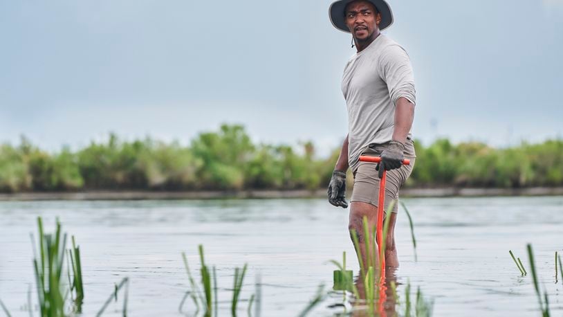 This image released by National Geographic shows actor/host Anthony Mackie wading in the Bayous near Violet, La., during the filming of "Shark Beach with Anthony Mackie." (Brian Roedel/National Geographic via AP)