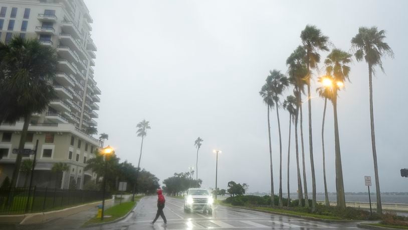 A person walks under light rain ahead of the arrival of Hurricane Milton, Wednesday, Oct. 9, 2024, in Tampa, Fla. (AP Photo/Julio Cortez)