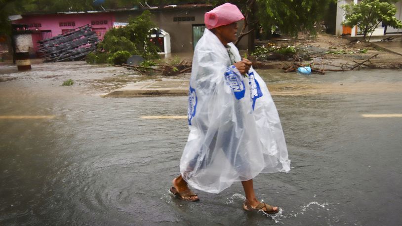 A person wearing plastic walks in the street after the passing of Hurricane John in Marquelia, Mexico, Tuesday, Sept. 24, 2024. (AP Photo/Luis Alberto Cruz)