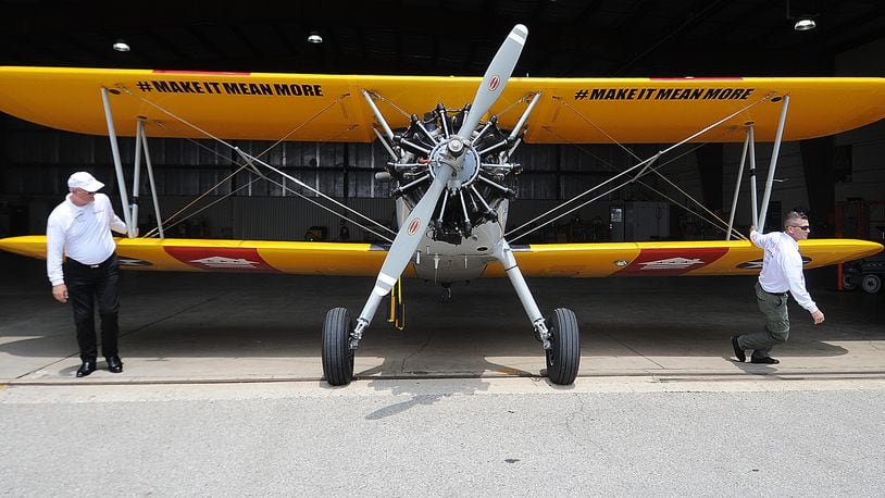 Leaders of Dream Flight, a nonprofit that works with seniors and veterans, pulls their Stearman out of a hangar of Dayton International Airport on Wednesday. The Stearman will be on display during the Dayton Air Show. MARSHALL GORBY\STAFF