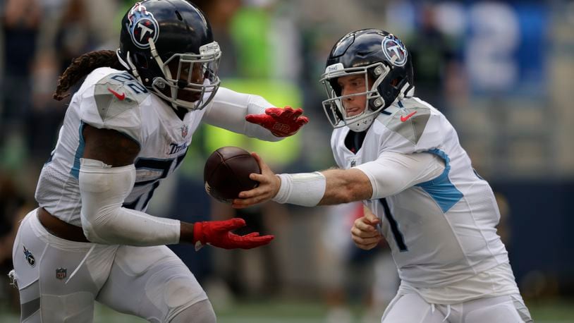 Tennessee Titans quarterback Ryan Tannehill, right, hands off to running back Derrick Henry during the second half of an NFL football game against the Seattle Seahawks, Sunday, Sept. 19, 2021, in Seattle. The Titans won 33-30 in overtime. (AP Photo/John Froschauer)