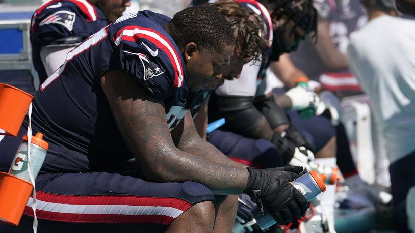 New England Patriots offensive tackle Trent Brown (77) and his teammates sit on the sidelines during the second half of an NFL football game against the Miami Dolphins, Sunday, Sept. 11, 2022, in Miami Gardens, Fla. The Dolphins defeated the Patriots 20-7. (AP Photo/Lynne Sladky)