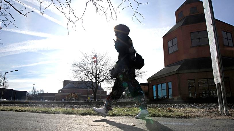 A woman walks in the sunshine Thursday, Feb. 1, 2024 as she makes her way along the Simon Kenton Trail in downtown Springfield. BILL LACKEY/STAFF