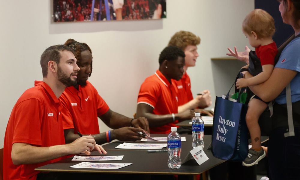 Dayton players, including Jacob Conner, left, sign autographs during a meet and greet with fans on Wednesday, Oct. 9, 2024, at UD Arena. David Jablonski/Staff