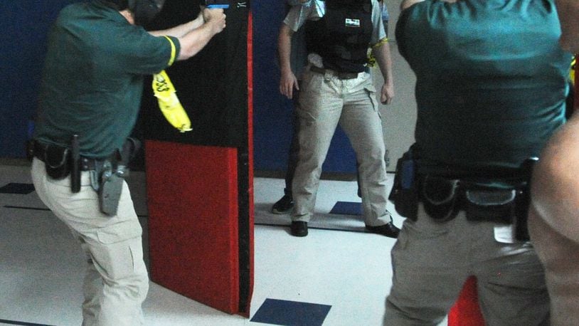 Cadets Chris Jones and Noah Wollum face off against Sinclair Police Academy Commander Joe Niehaus in a mock domestic dispute situation at Sinclair Police Academy. Reporter London Bishop is the hostage in this scenario. MARSHALL GORBY\STAFF