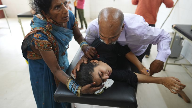 FILE - A father tries to calm his daughter suffering from a heat-related ailment as she is brought to the government district hospital in Ballia, Uttar Pradesh state, India, June 19, 2023. The official number of heat deaths listed in government reports barely scratches the surface of the true toll and that's affecting future preparations for similar swelters, according to public health experts. (AP Photo/Rajesh Kumar Singh, File)
