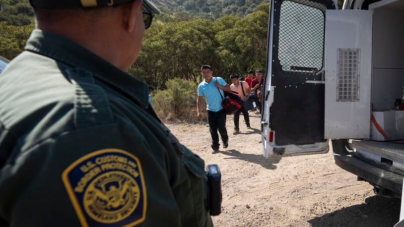 A Border Patrol agent leads a group of migrants seeking asylum towards a van to be transported and processed, Wednesday, June 5, 2024, near Dulzura, Calif. President Joe Biden on Tuesday unveiled plans to enact immediate significant restrictions on migrants seeking asylum at the U.S.-Mexico border as the White House tries to neutralize immigration as a political liability ahead of the November elections. (AP Photo/Gregory Bull)