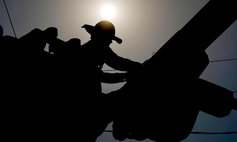 FILE - A linesman works on power lines under the morning sun, July 12, 2024, in Phoenix. (AP Photo/Matt York, File)