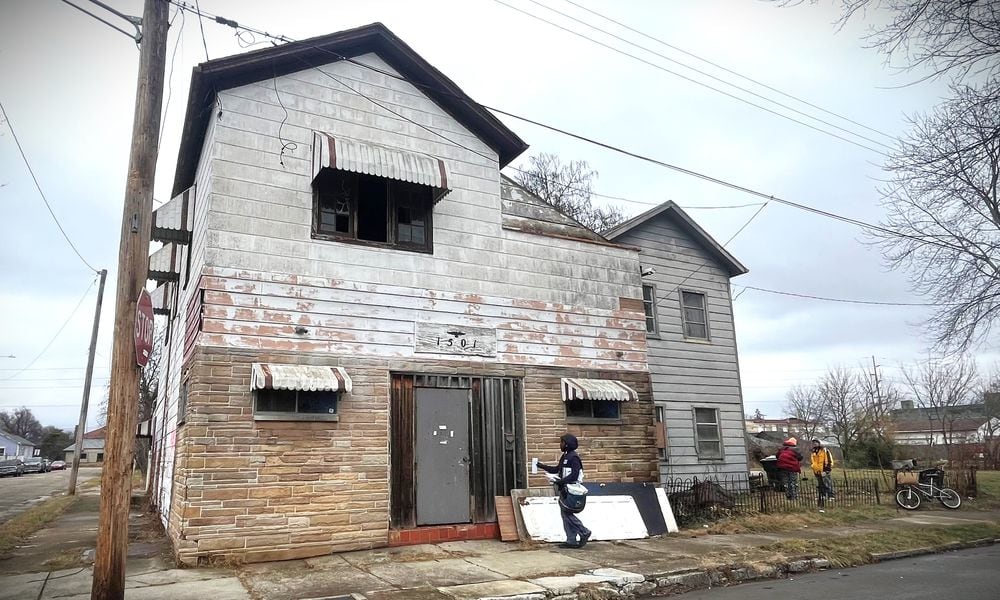 A postal worker delivers mail to a property in East Dayton that auditor records show owes more than $24,000 in unpaid taxes. CORNELIUS FROLIK / STAFF