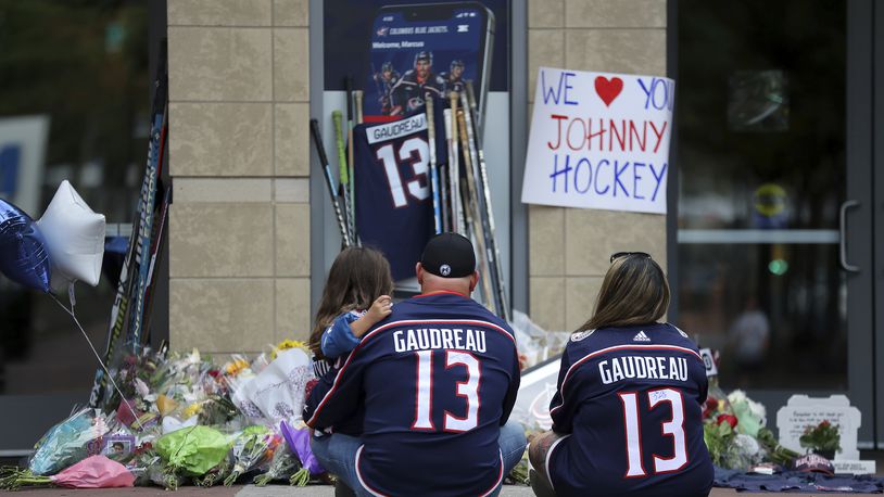 Shiloh Rivera, left, mourns with Hylas Stemen, center, and Amanda Rivera of Columbus, at the makeshift memorial set up by fans for Blue Jackets hockey player Johnny Gaudreau in Columbus, Ohio, Aug. 30, 2024. Gaudreau, along with his brother Matthew, was fatally struck by a motorist while riding his bicycle on Thursday. (AP Photo/Joe Maiorana)