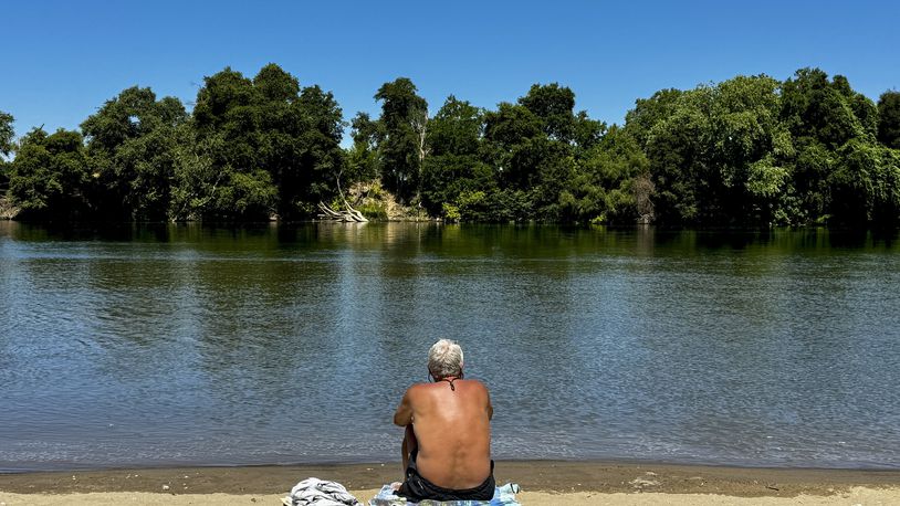 A man cools off by the river in Sacramento, Calif., Tuesday, July 2, 2024. Swaths of California sweltered Tuesday, and things were only expected to get worse during the Fourth of July holiday week for parts of the United States with nearly 90 million people under heat alerts. (AP Photo/Terry Chea)
