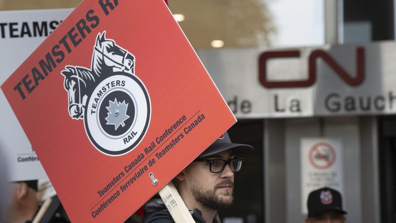 Rail workers picket in front of Canadian National headquarters on the first day of a nationwide rail shutdown, after workers were locked out by CN and CPKC when new contract agreements weren't reached by the midnight deadline, in Montreal, Thursday, Aug. 22, 2024. (Ryan Remiorz /The Canadian Press via AP)