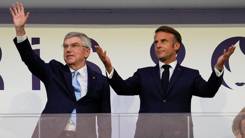 FILE - IOC President Thomas Bach and French President Emmanuel Macron wave during the 2024 Summer Olympics closing ceremony at the Stade de France, Aug. 11, 2024, in Saint-Denis, France. (AP Photo/Ashley Landis, File)