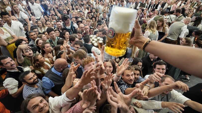 Festival goer reach out for the first glasses of beer on day one of the 189th 'Oktoberfest' beer festival in Munich, Germany, Saturday, Sept. 21, 2024. (AP Photo/Matthias Schrader)