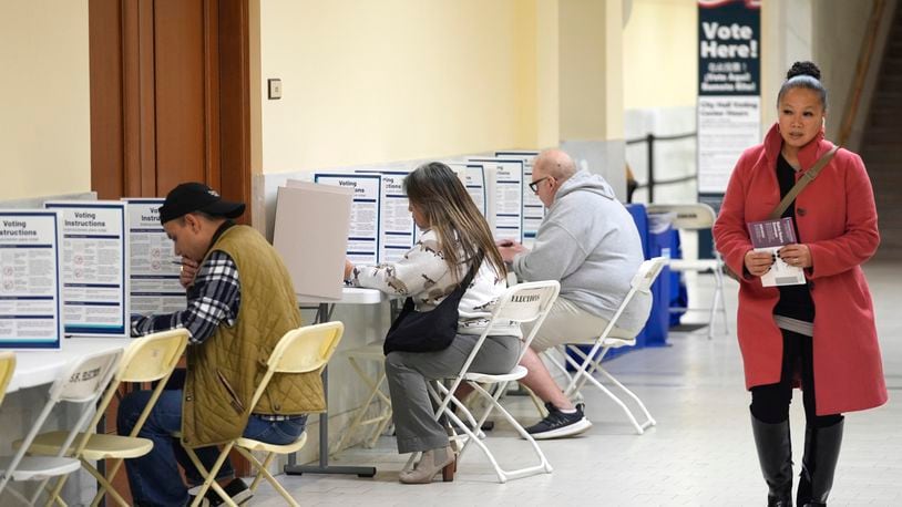 FILE - A woman walks with her ballot to a vacant voting booth at City Hall in San Francisco, March 5, 2024. (AP Photo/Eric Risberg, File)