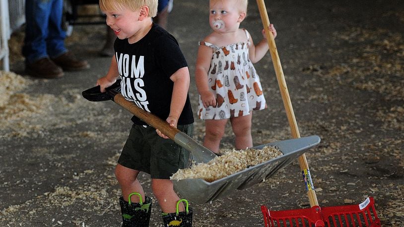 Weston Sandberg, age 3, and his sister Isabella, age 1, help clean up the swine barn Wed. Aug. 16, 2023 at the Miami County Fair. MARSHALL GORBY\STAFF