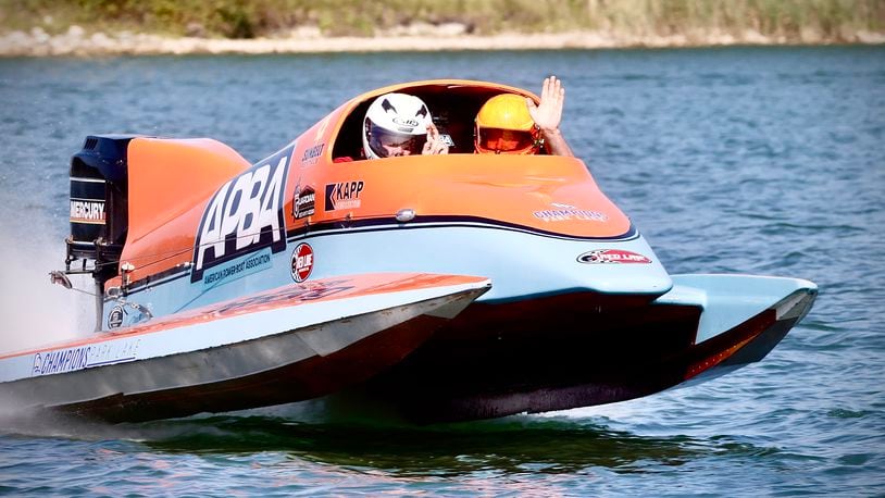 State Representative Bernie Willis, left, and F1 racing champion Chris Fairchild give a wave as they go for a ride on media day Wednesday, August 21, 2024 in a two seat high performance boat for the upcoming Wake the Lake, at Champion Park Lake. MARSHALL GORBY\STAFF