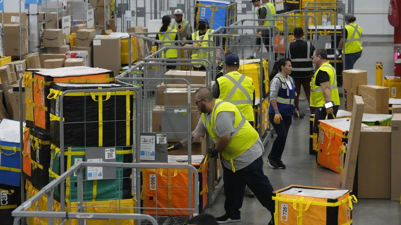 FILE - Amazon employees load packages on carts before being put on to trucks for distribution to customers for Amazon's annual Prime Day event at an Amazon's DAX7 delivery station on July 16, 2024, in South Gate, Calif. (AP Photo/Richard Vogel, File)