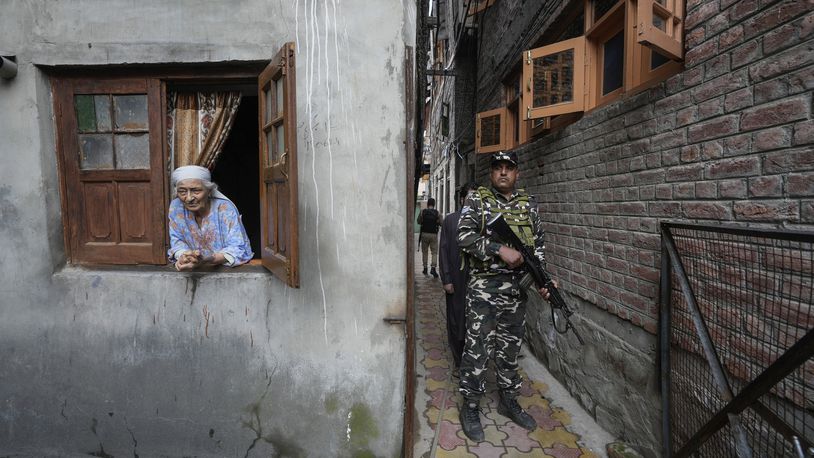 An elderly Kashmiri woman looks on as a paramilitary soldier guard during the door-to -door election campaigning by Bharatiya Janata Party (BJP) candidate ahead of the Jammu and Kashmir state assembly elections, in Srinagar, Indian controlled Kashmir,Thursday, Aug. 29, 2024. (AP Photo/Mukhtar Khan)