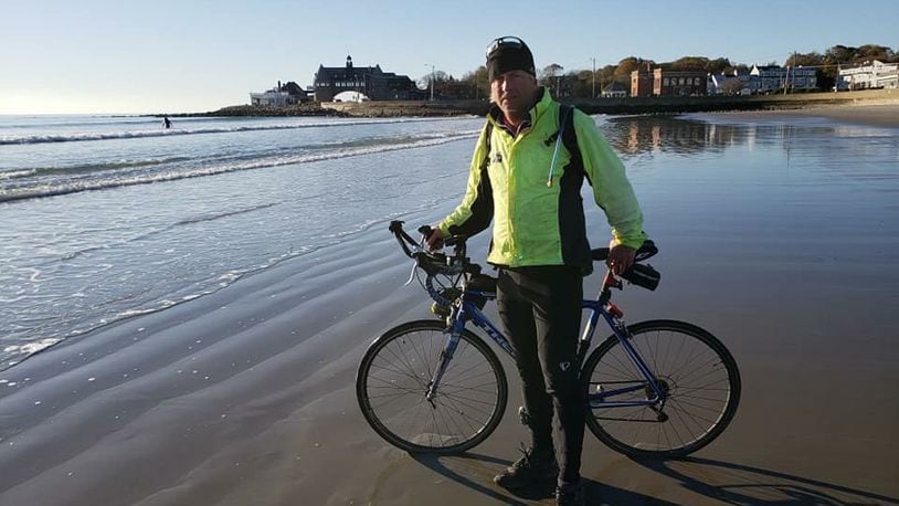 Earl McDaniel ceremoniously dips his bike tire in the Narragansett Bay marking the end of his cross-country bike trip. CONTRIBUTED