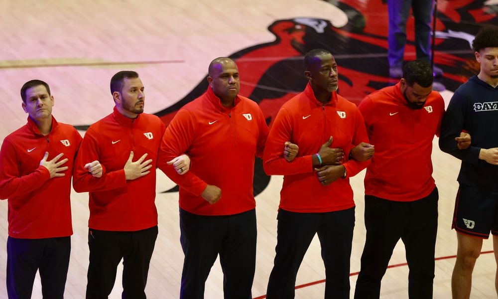 Dayton coaches stand for the national anthem before a game against Saint Josephs on Tuesday, Feb. 6, 2024, at Hagan Arena in Philadelphia. David Jablonski/Staff