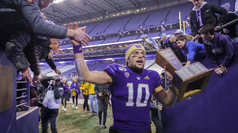 FILE - Washington quarterback Jacob Eason high fives fans as he leaves the field with the Apple Cup after an NCAA college football game against Washington State, Nov. 29, 2019 in Seattle. (AP Photo/Stephen Brashear, File)