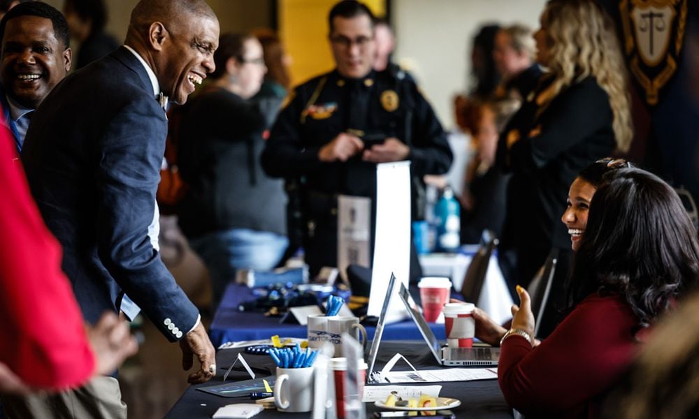 Dayton Public Schools employee Gary Armstrong, left talks with representatives from the city of Dayton Wednesday April 10, 2024. Sinclair hosted the fair which attracted near 100 employers. JIM NOELKER/STAFF