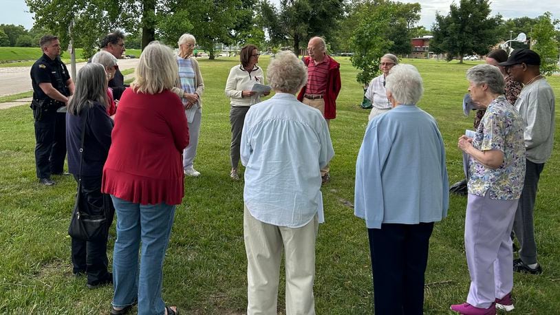 Two Dayton police officers join a group of Dayton-area residents holding a prayer vigil for homicide victims June 8, 2024, at McIntosh/Riverview Park in Dayton. JEREMY P. KELLEY / STAFF