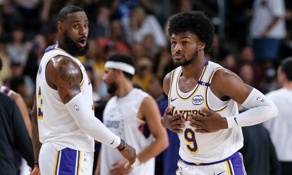 Los Angeles Lakers guard Bronny James (9), right, steps onto the court with Los Angeles Lakers forward LeBron James (23) during the first half of a preseason NBA basketball game Sunday, Oct. 6, 2024, in Palm Desert, Calif. (AP Photo/William Liang)