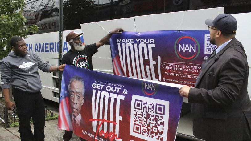 Organizers with the National Action Network put up banners for a Get Out the Vote event as the prepare to depart on a bus tour toward Philadelphia in the Harlem neighborhood of New York on Friday, Sep. 27, 2024. (AP Photo/Noreen Nasir)