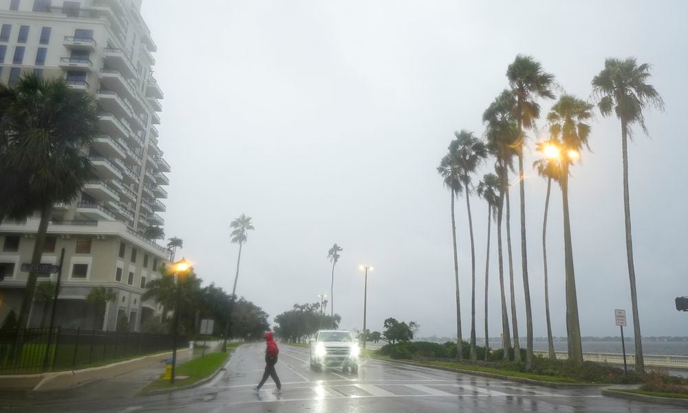 A person walks under light rain ahead of the arrival of Hurricane Milton, Wednesday, Oct. 9, 2024, in Tampa, Fla. (AP Photo/Julio Cortez)