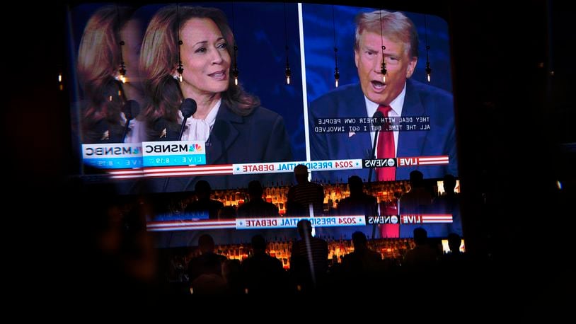 Reflected in a mirror, people watch the presidential debate between Republican presidential nominee former President Donald Trump and Democratic presidential nominee Vice President Kamala Harris, Tuesday, Sept. 10, 2024, at the Gipsy Las Vegas in Las Vegas. (AP Photo/John Locher)